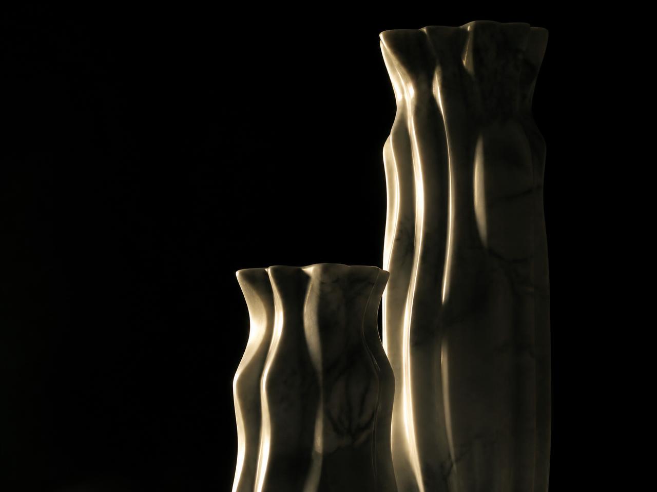 Duas colunas de mármore de alturas diferentes iluminadas em champanhe